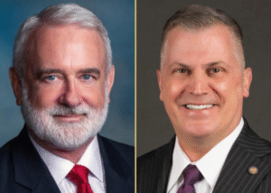 Side-by-side portraits of two men in suits, both embodying leadership. The man on the left has white hair, a beard, and a red tie. The man on the right—smiling—has short gray hair and wears a striped suit with a purple tie, reminiscent of Valley Forge Military College decorum.